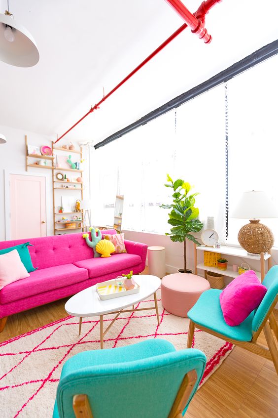 غرفة معيشة ملونة بها أريكة وردية ، وكراسي فيروزية