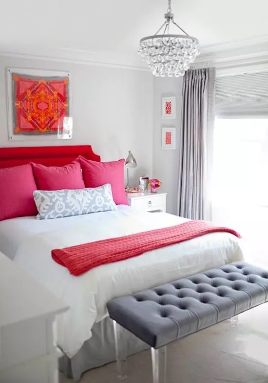 غرفة نوم رمادية اللون مع سرير منجد باللون الأحمر الجريء