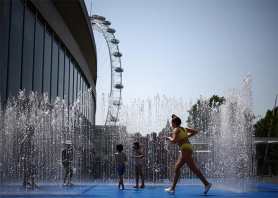 أطفال يستريحون في نافورة مياه خلال موجة حارة في لندن