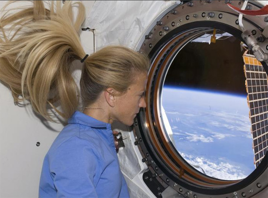 رائدة الفضاء كارين نيبيرج تنظر من خلال نافذة في مختبر كيبو