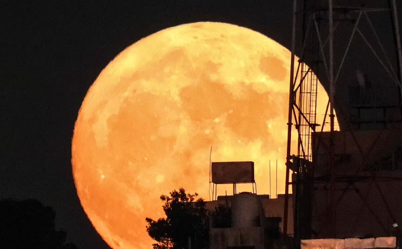 القمر العملاق يرتفع خلف مبانٍ في عمان
