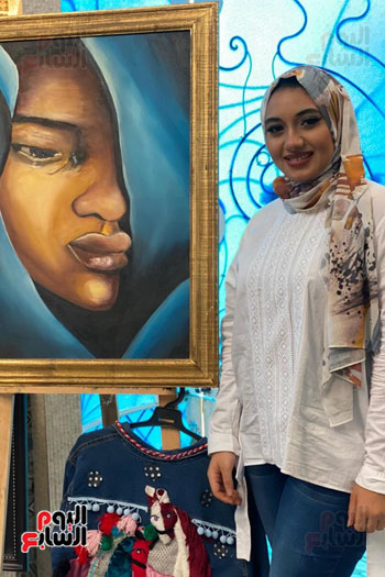 الفنانة مع إحدى لوحاتها
