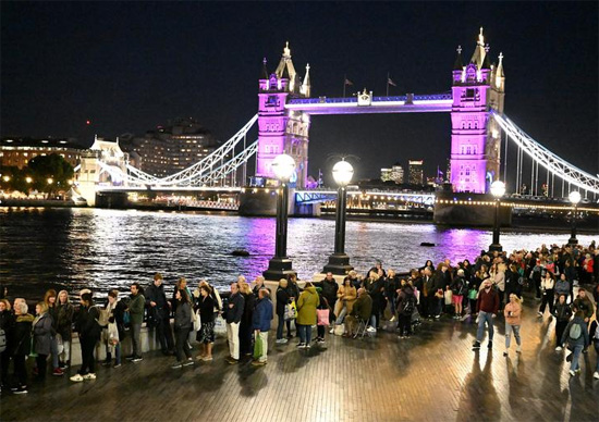 الناس ينتظرون في طابور للتعبير عن احترامهم حيث أضاء جسر البرج باللون الأرجواني