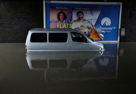سيارة غارقة جزئيا في المياه بعد هطول أمطار غزيرة على جزء من الطريق في ستوكبورت ببريطانيا