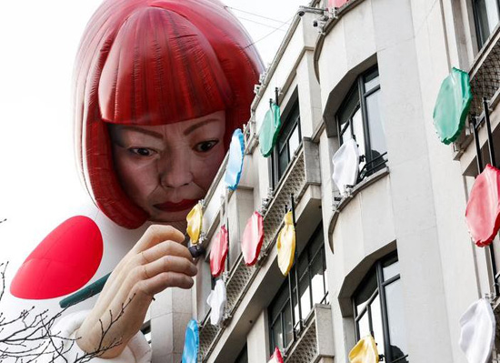 تركيب تمثال عرض أزياء كبير قابل للنفخ يصور الفنان الياباني يايوي كوساما يطل على متجر لويس فويتون الرئيسي في شارع الشانزليزيه في باريس