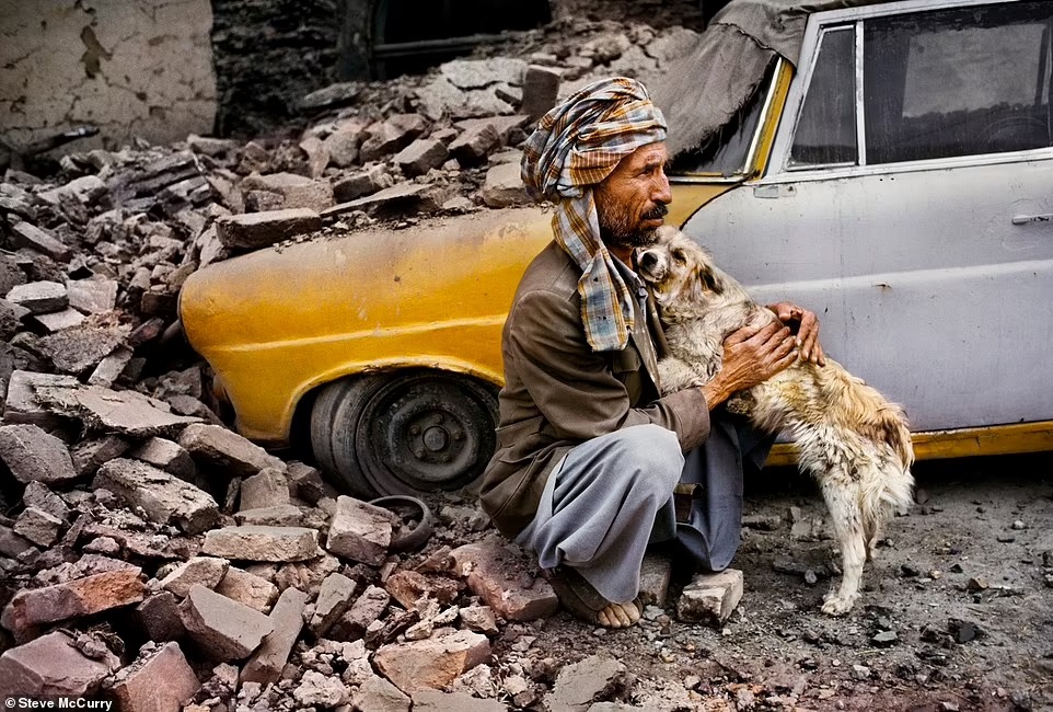 رجل يحتضن كلبه بجوار سيارة أثناء القصف في كابول عام 1992.