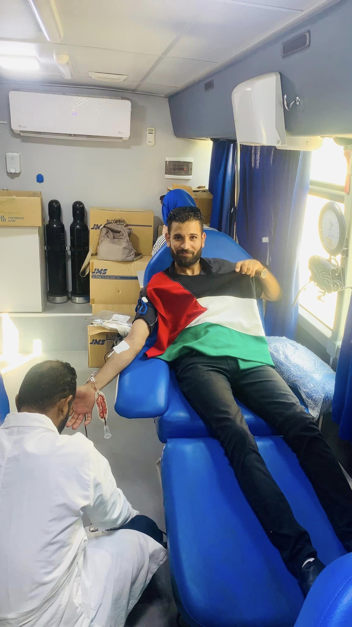 شاب بعلم فلسطين خلال التبرع بالدم فى الحملة
