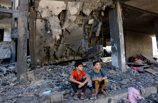طفلان يجلسان على ركام منزلهم المهدم في غزة بعد القصف