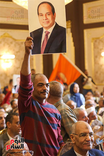 أحد العاملين يرفع صور الرئيس السيسى