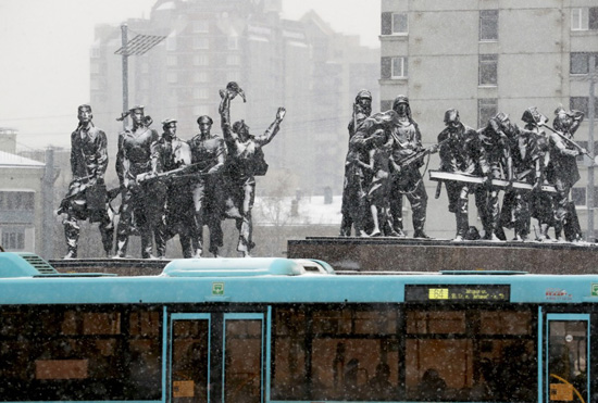 أشخاص على متن حافلة يمرون بالقرب من النصب التذكاري للمدافعين الأبطال