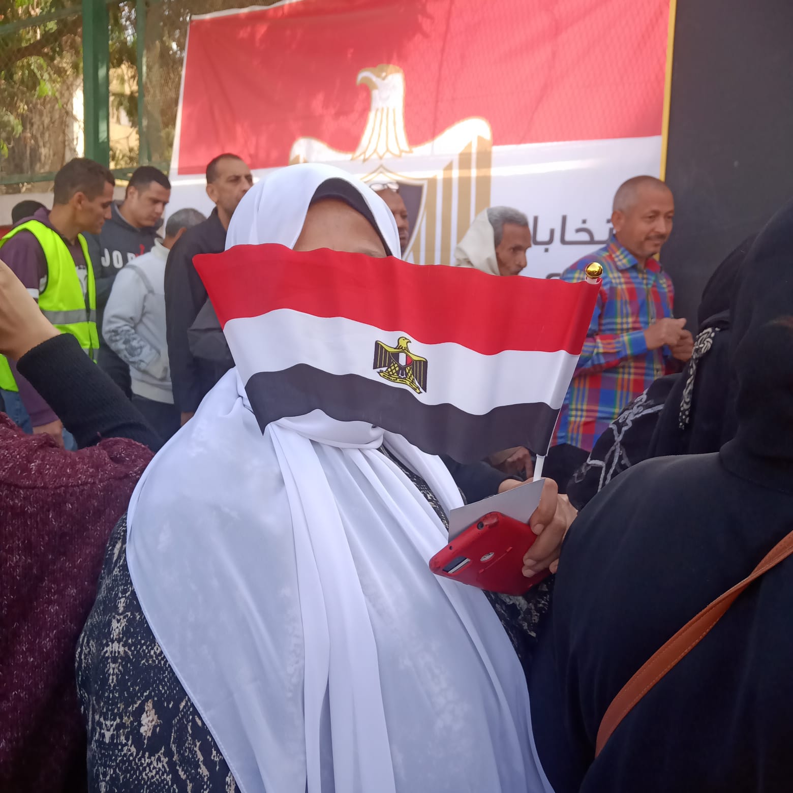 سيدة تحمل علم مصر أمام لجنتها الانتخابية