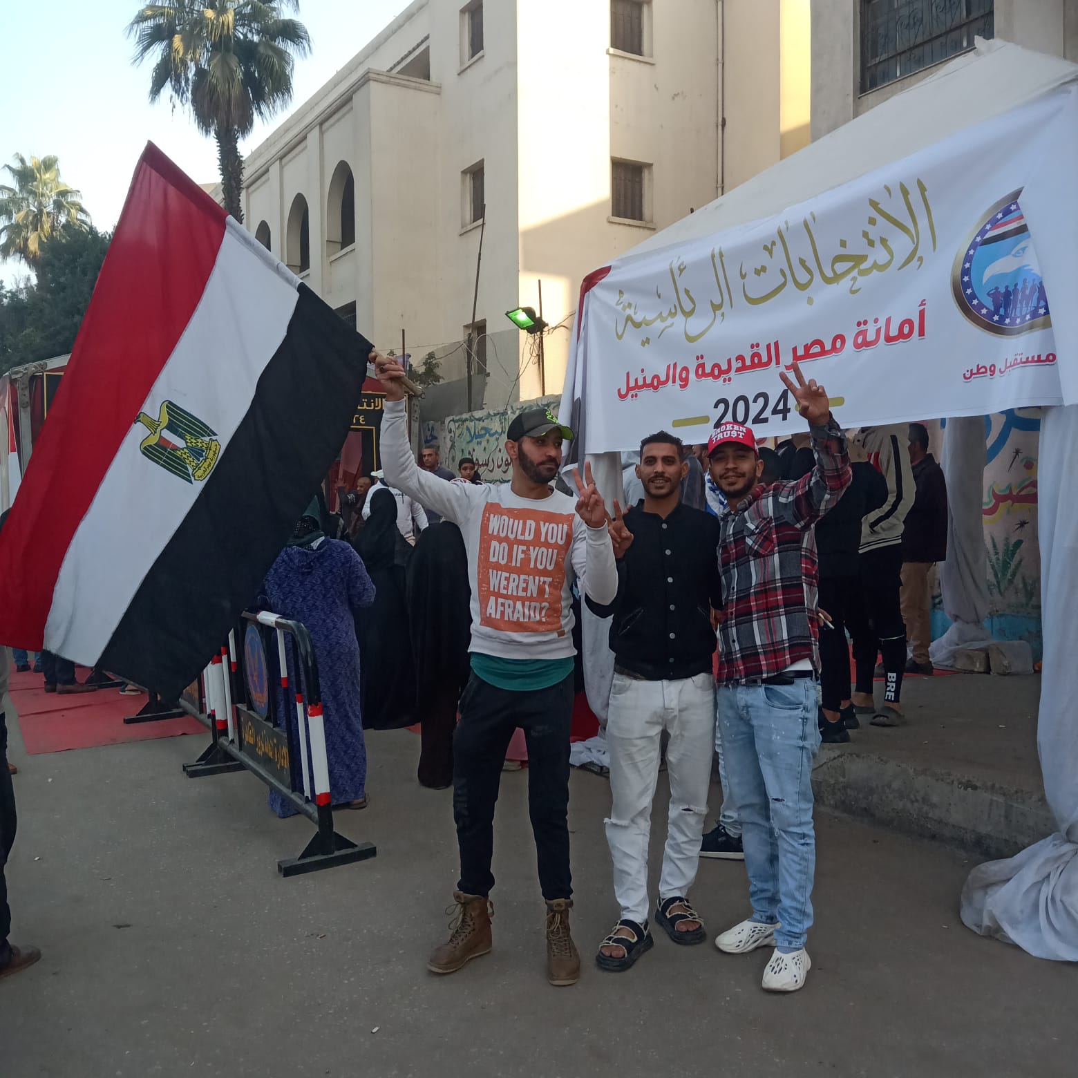 شباب يرفعون علم مصر عاليًا أمام اللجان الانتخابية