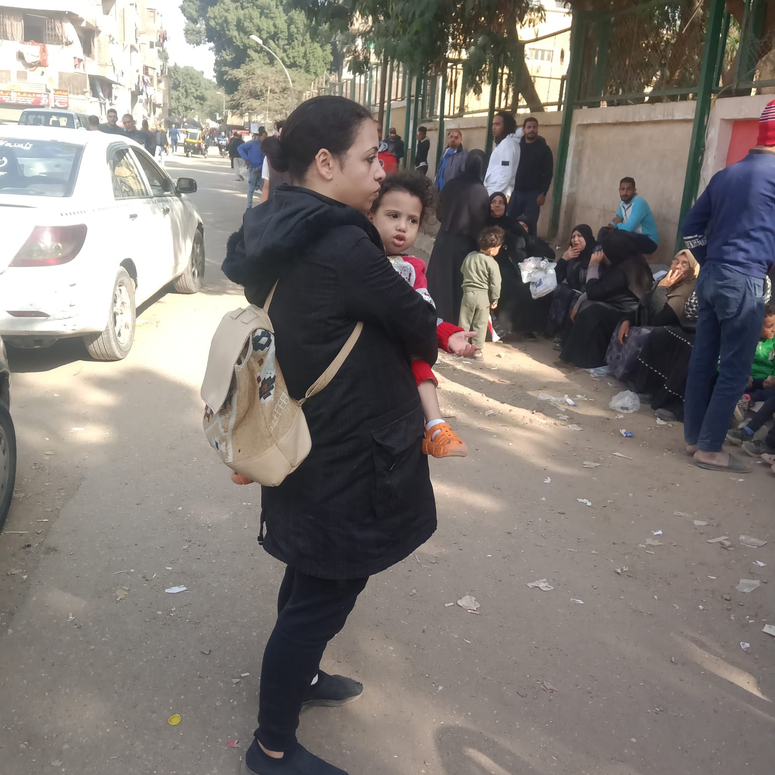 ناخبة تحمل ابنتها أمام لجنتها الانتخابية بمصر القديمة