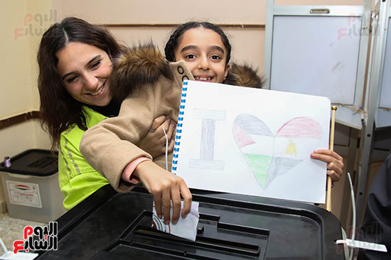 طفلة تشارك أسرتها التصويت بالانتخابات بكراسة رسم ورسمة لعلم مصر وفلسطين (1)