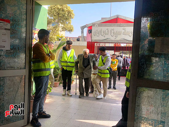 متطوعون يساعدون ذوى الهمم وكبار السن فى الوصول للجانهم الانتخابية (1)