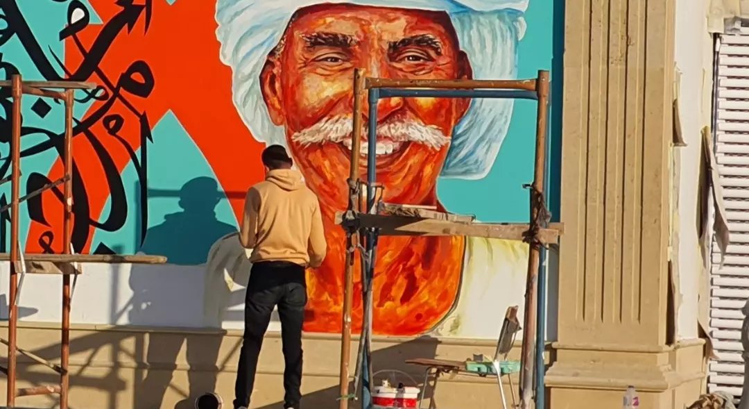 الشاب محمود سنوسي خلال العمل فى جدارية الكورنيش