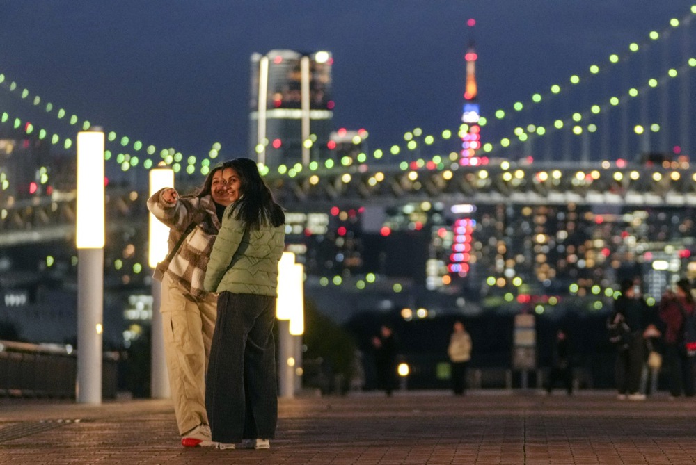 يستمتع السائحون الأجانب بالمنظر الليلي لجسر قوس قزح وبرج طوكيو