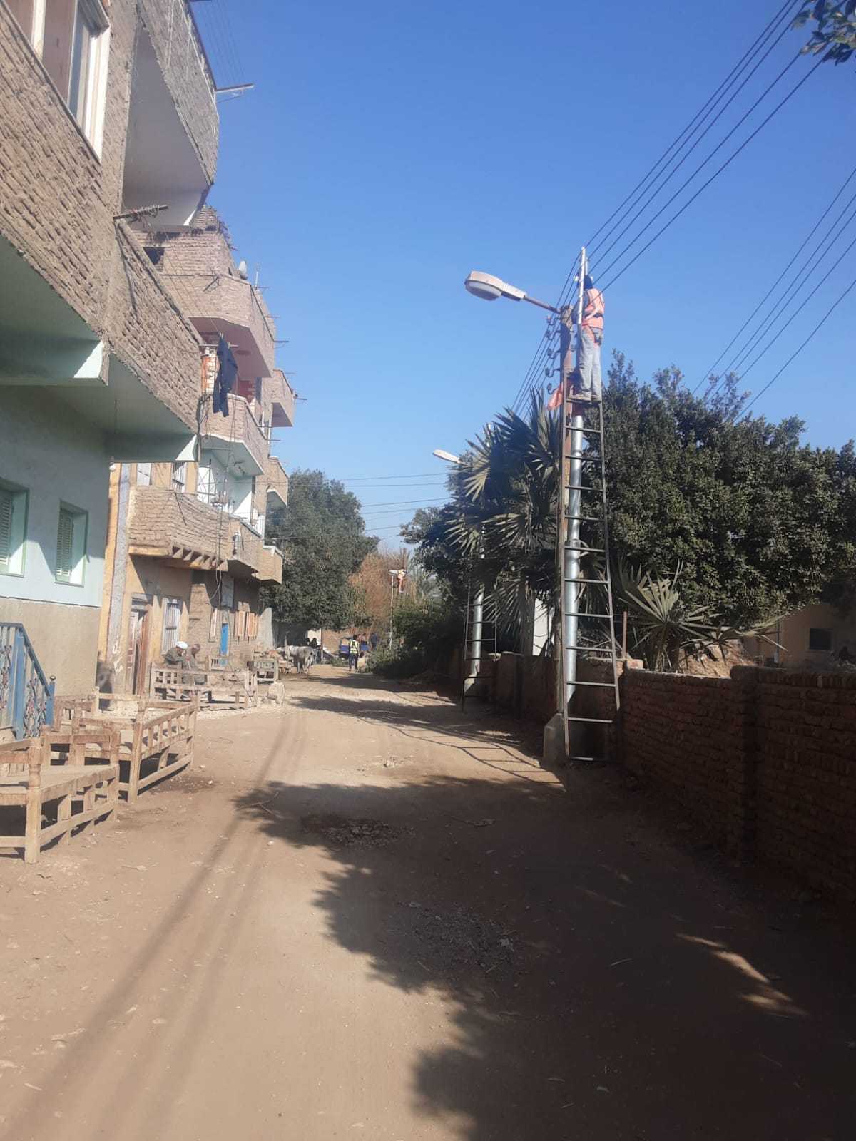 أعمال توصيل أسلاك الكهرباء بالأعمدة الجديدة فى قرية النمسا