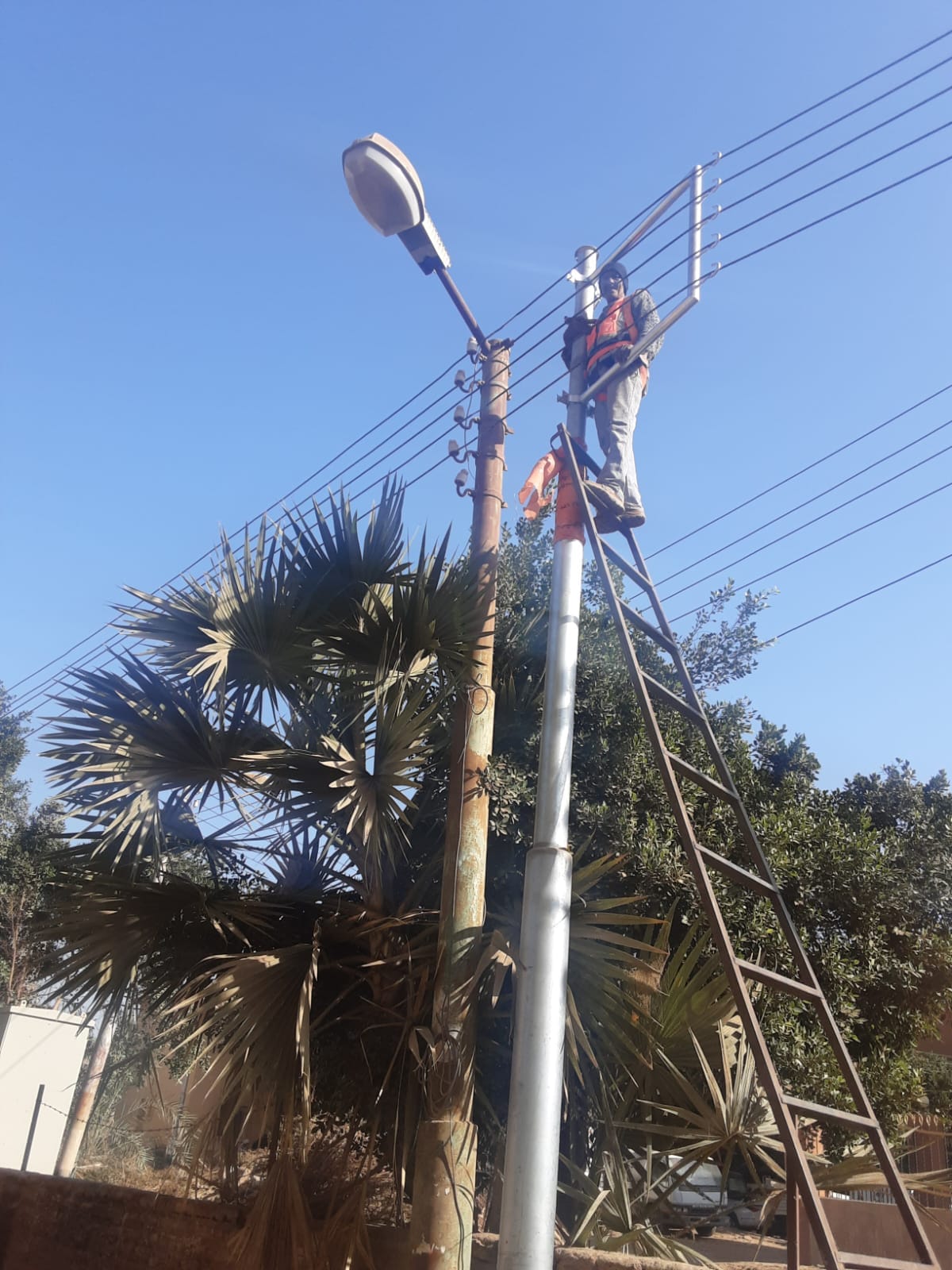 جانب من توصيل أسلاك الكهرباء بالأعمدة الجديدة فى قرية النمسا