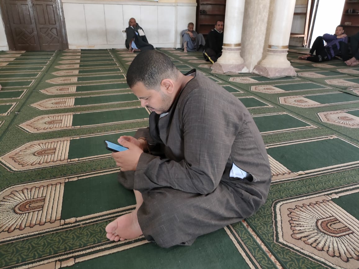 أحد الأهالى يتلو القرآن على تطبيق بالهاتف المحمول