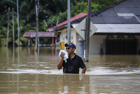 رجل-يخوض-في-منطقة-غمرتها-المياه-أثناء-هطول-الأمطار-في-يونغ-بينغ
