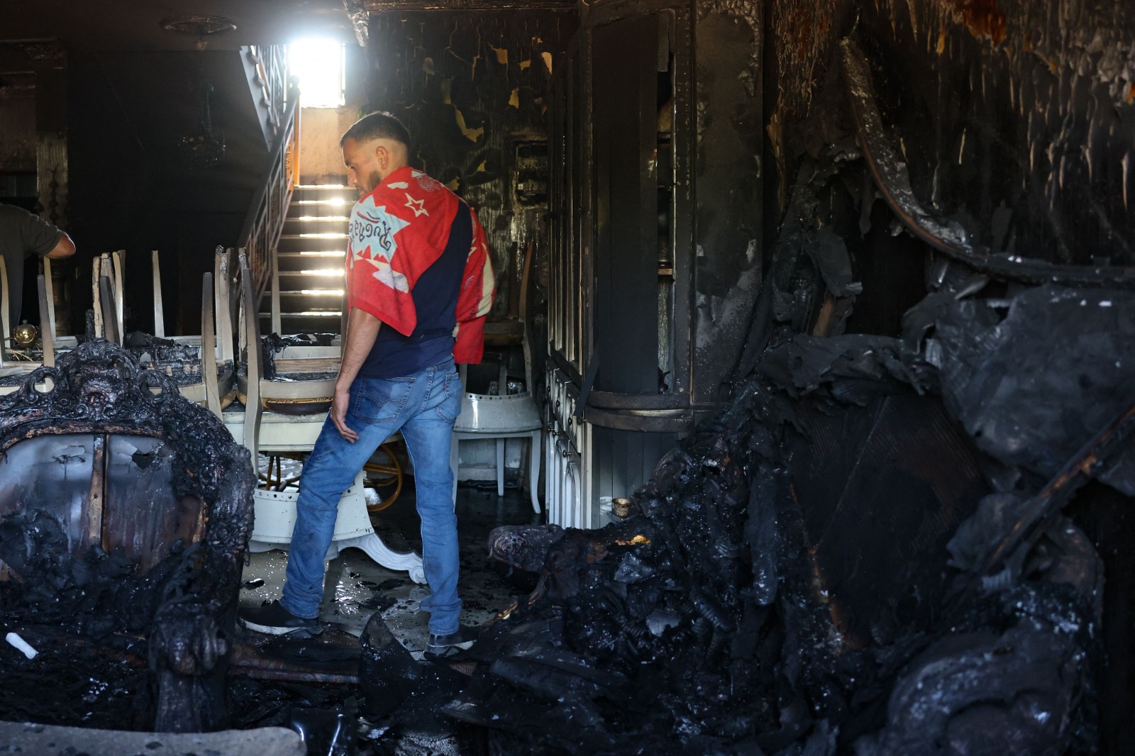 مواطن فلسطيني يتفقد آثار حرق المستوطنين الإسرائيليين لمنزله