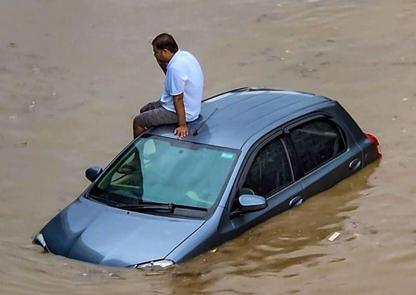 رجل محاصر على سيارة وسط المياه
