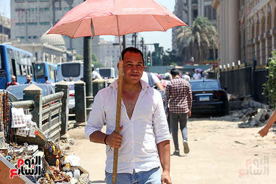 المواطنون يحملون الظلات للاحتماء من ارتفاع درجات الحراره  (1)