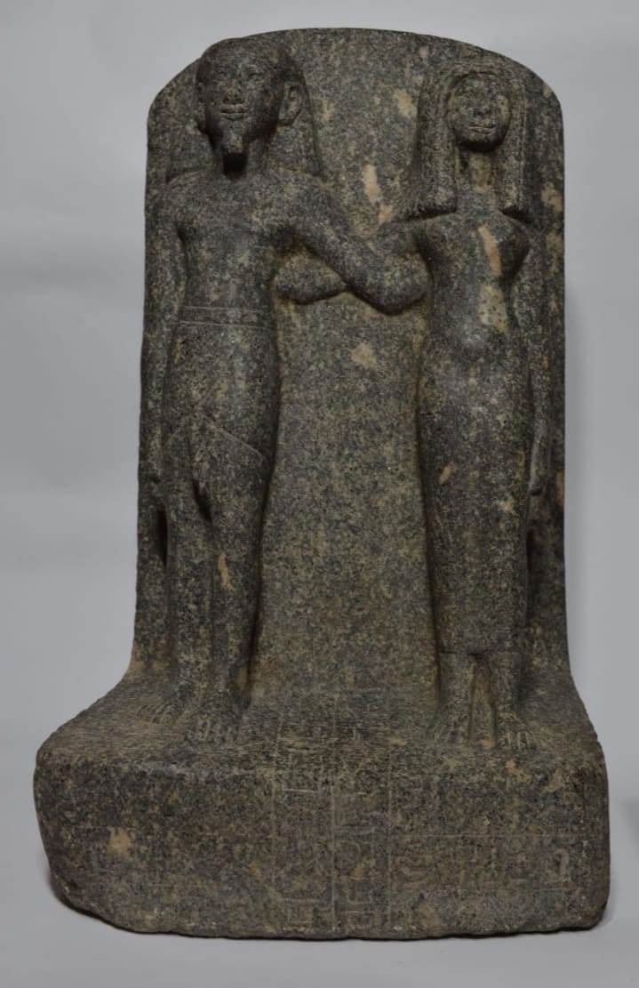 طعة من حجر الجرانيت الأسود عليه نقش بالبارز يمثل شخصان لرجل وسيدة بالوضع الواقف