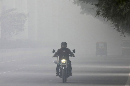 رجل يسير بدراجة نارية وسط تحذيرات من الطقس السيئ