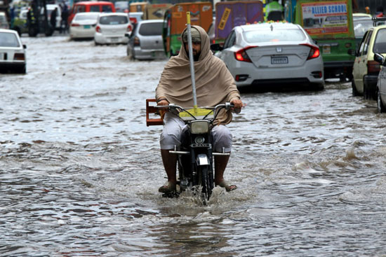 رجل يسير بدراجة نارية وسط الأمطار