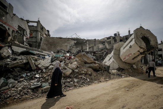 امرأة فلسطينية تسير بجوار أنقاض مسجد مدمر