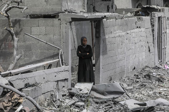 امراة تقف فى منزلها بعد قصف المنزل