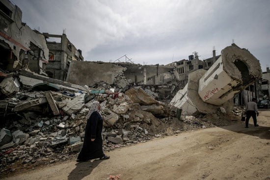 51680-امرأة-فلسطينية-تسير-بجوار-أنقاض-مسجد-مدمر