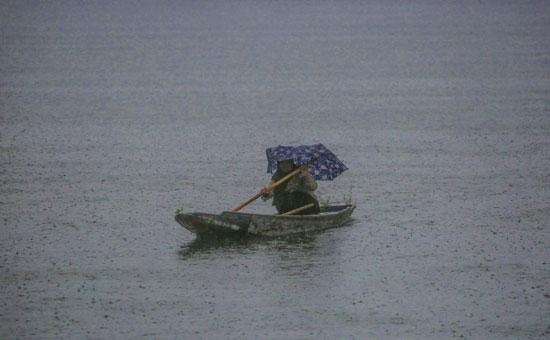 امرأة كشميرية تعبر مياه بحيرة دال أثناء الرياح والأمطار
