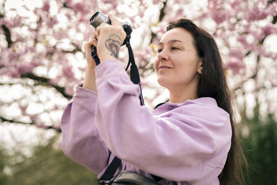 فتاة تلتقط الصور لزهرة الكرز