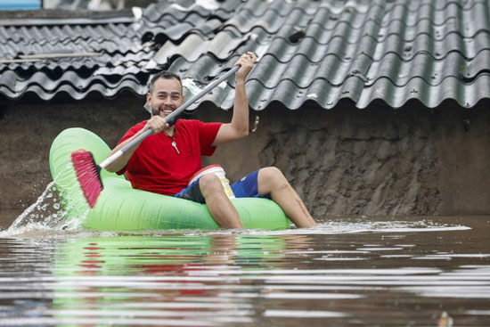 رجل يسير بعوامه مطاطة وسط الفيضانات