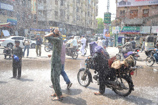 رجل يسير بدراجة نارية ورش المياه فى الشوارع