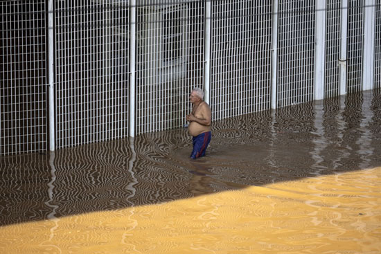 مسن برازيلى يسير وسط مياه الفيضانات