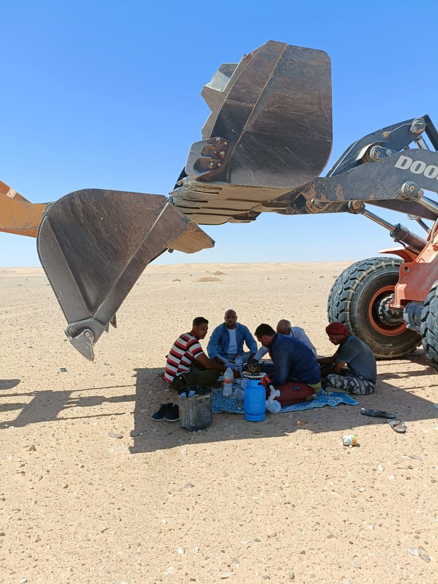 علماء مركز بحوث الصحراء يجلسون تحت  كبشة  اللودر لحمايتهم من أشعة الشمس
