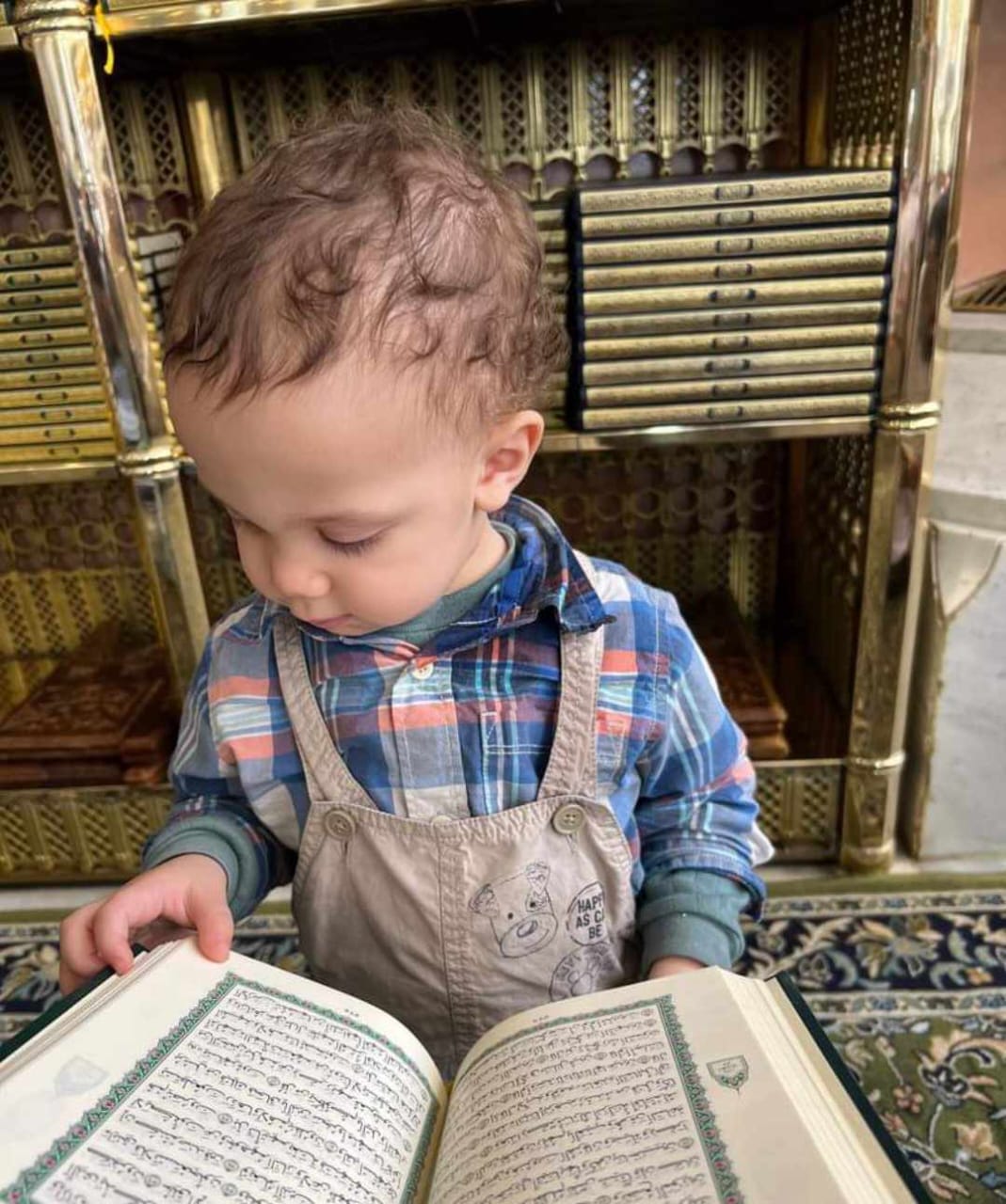 الطفل يحي أثناء تقليبه بصفحات المصحف بالمسجد النبوي