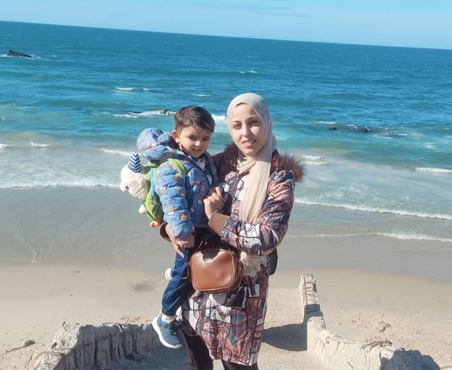 لميس الأقرع مع طفلها في إحدى مخيمات الشاطئ