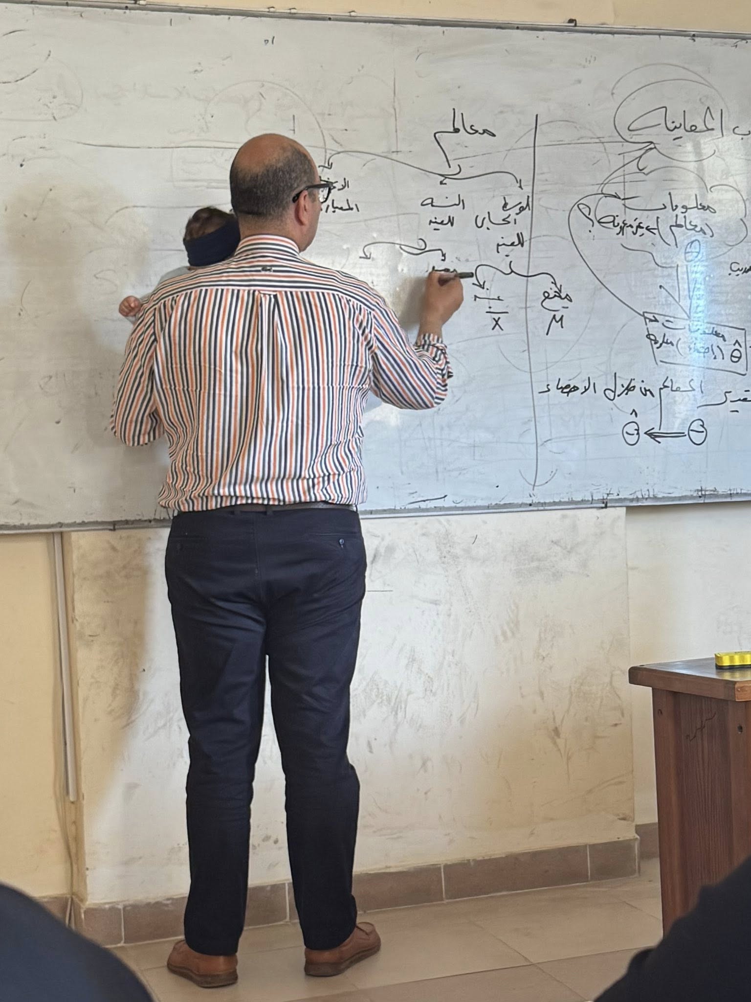 عميد كلية التجارة جامعة كفر الشيخ يشرح محاضرة ممسكا طفل
