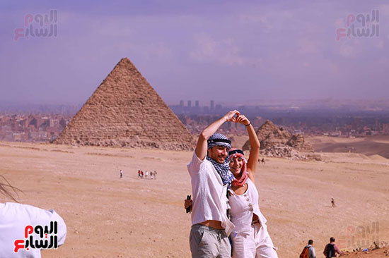 السياح يلتقطون صورا تذكارية مع الاهرامات