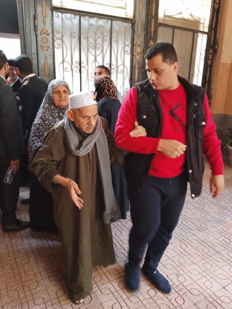 موظف بلجنة فرعية يساعد رجل مسن للإدلاء بصوته في الانتخابات