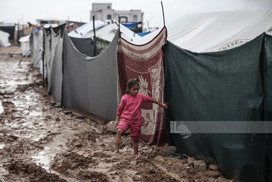 طفله تسير وسط الطين الناجم عن مياه الأمطار