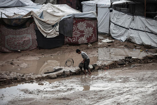 طفل يحالو بناء سد لمنع تدفق مياه الأمطار الى الخيام