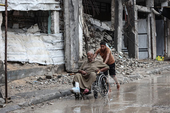 رجل مسن على كرسى متحرك وسط مياه الأمطار