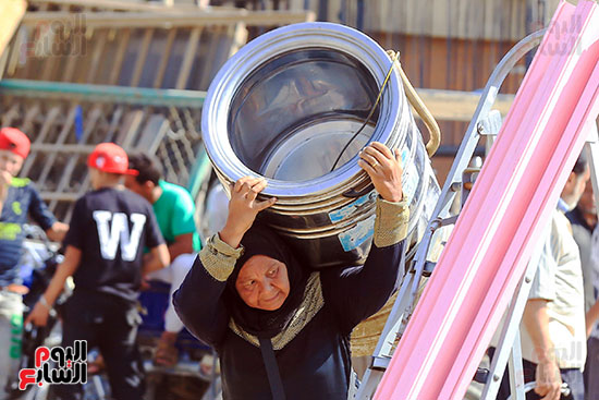 سيدة تحمل غسالة بعد شرائها من الخردة