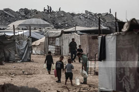 طفال فلسطينيون يحملون جراكن المياه في مخيم البريج وسط غزة، مع استمرار أزمة نقص المياه الخانقة في القطاع